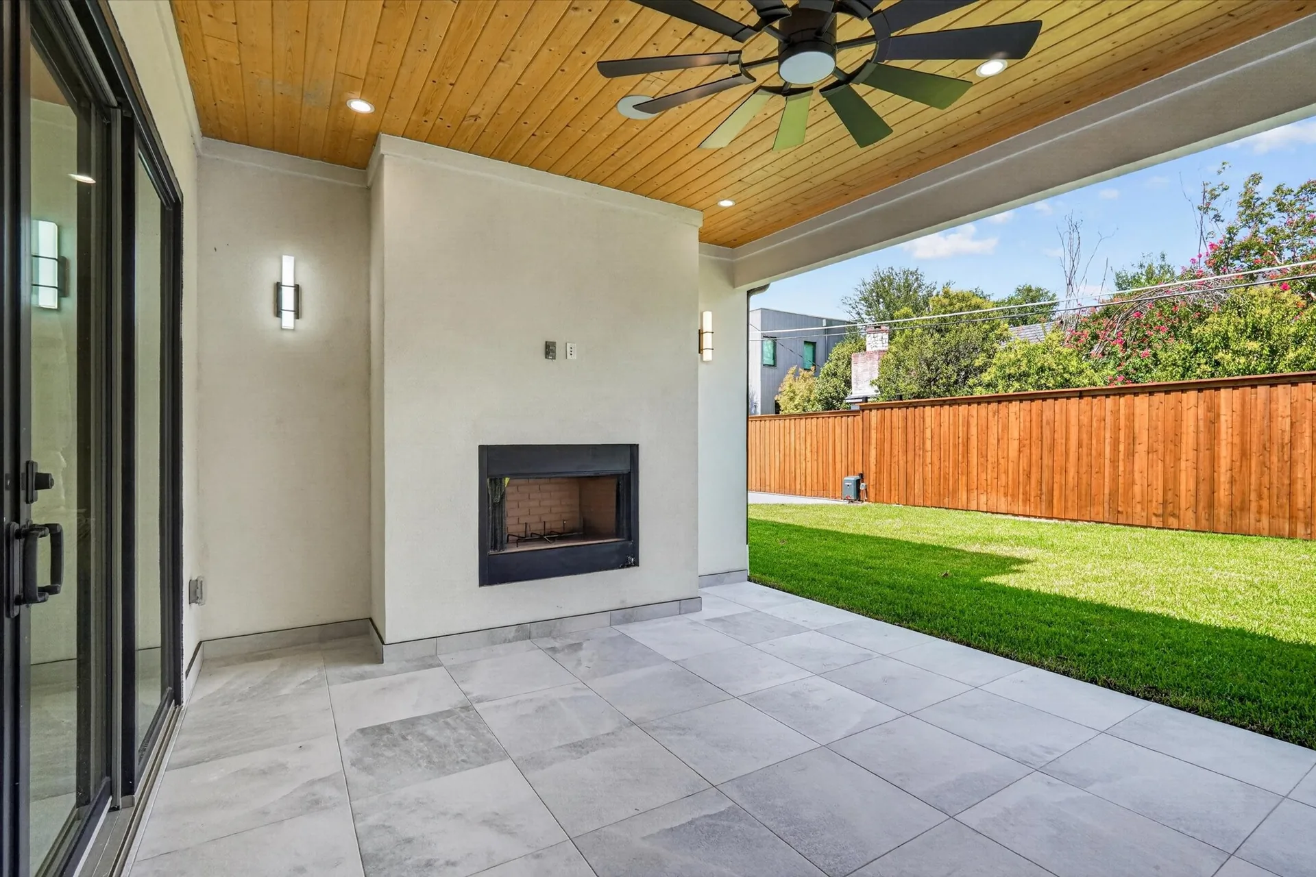 A covered outdoor room with a fireplace, seating and a view across the lawn.