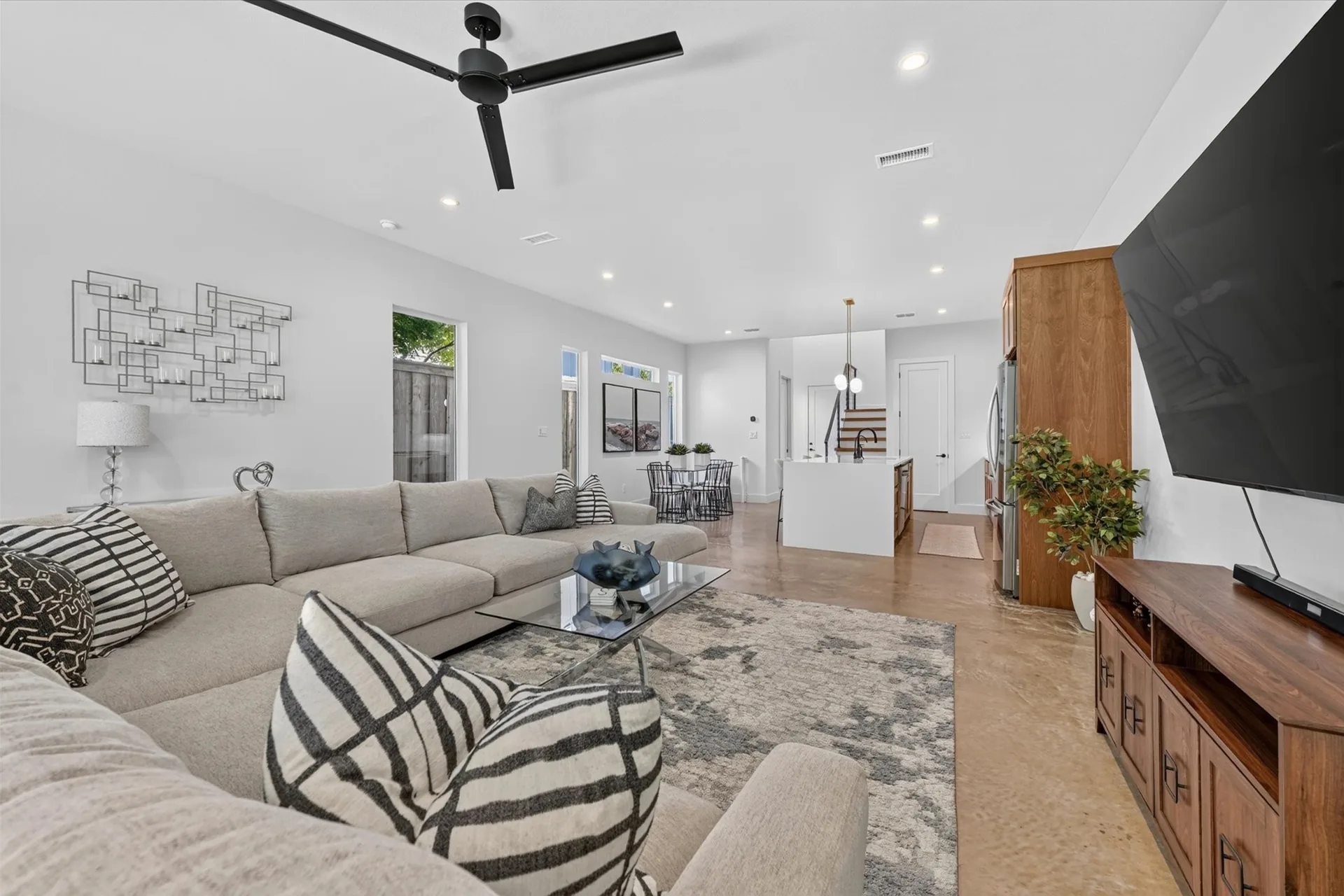 A staged living room with a pale sofa, timber floors and large windows onto the garden.