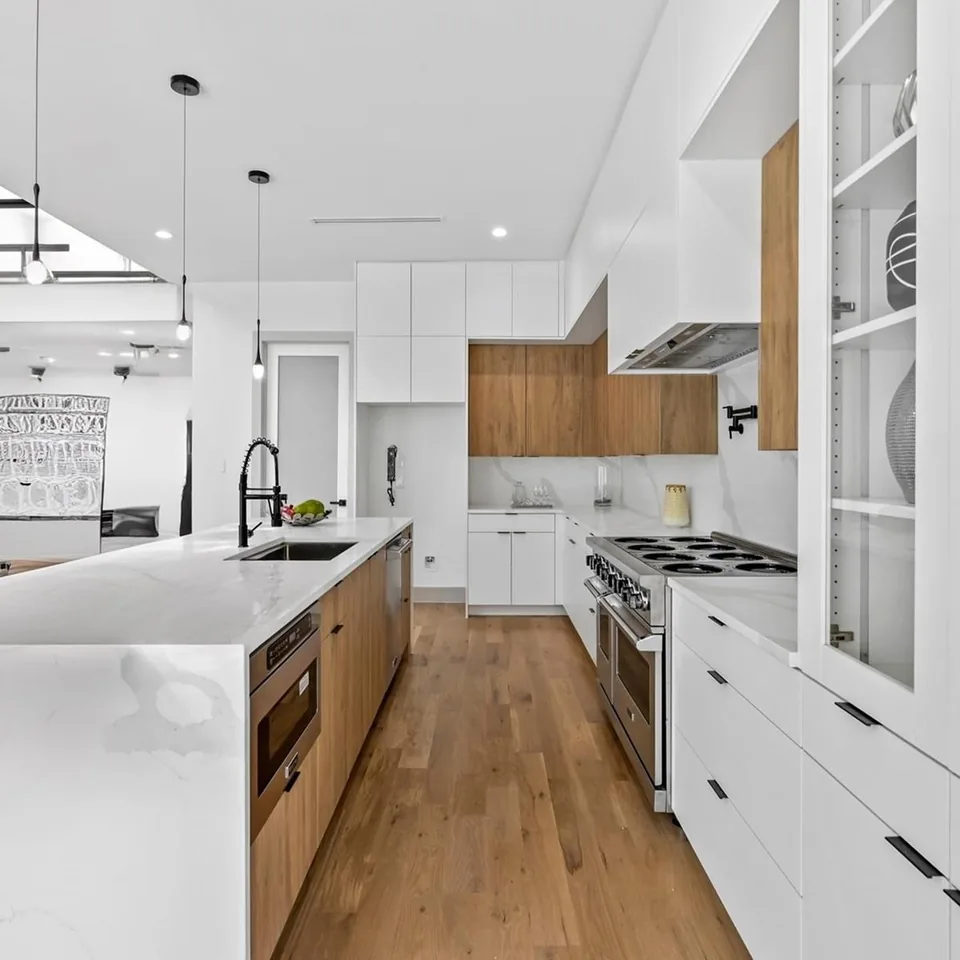 A newly finished kitchen with a pale island, timber floors and glass-fronted cabinetry.